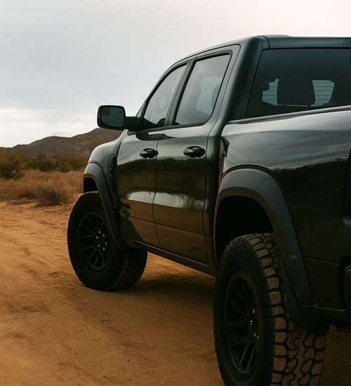 Rugged black pickup truck driving on a dusty Arizona desert trail, emphasizing durable protection on high-wear areas