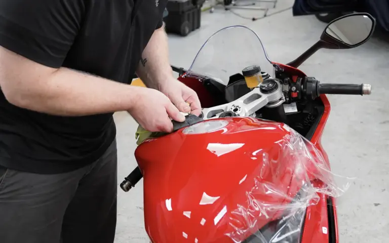 Technician installing XPEL Paint Protection Film on a red sport motorcycle

