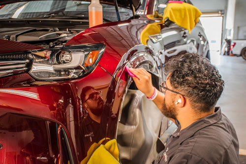 PPF technician installing XPEL film on front fender in Tucson