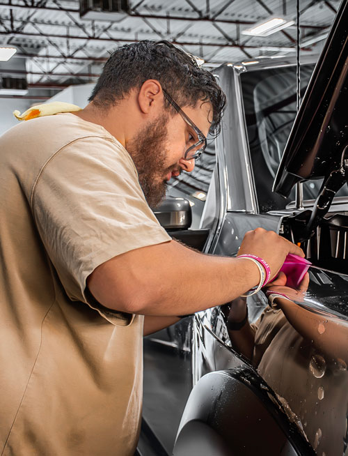 Certified installer applying XPEL Ultimate Plus PPF to a luxury truck in Tucson